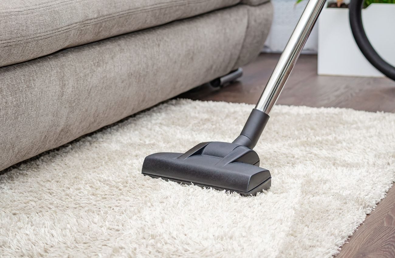 Deep Clean Carpet Services for Homes & Offices A vacuum cleaner is shown cleaning a white rug, highlighting a carpet cleaning service located in San Antonio, TX.